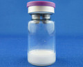 A see-through vial with a purple cap that contains a white cake-like substance.